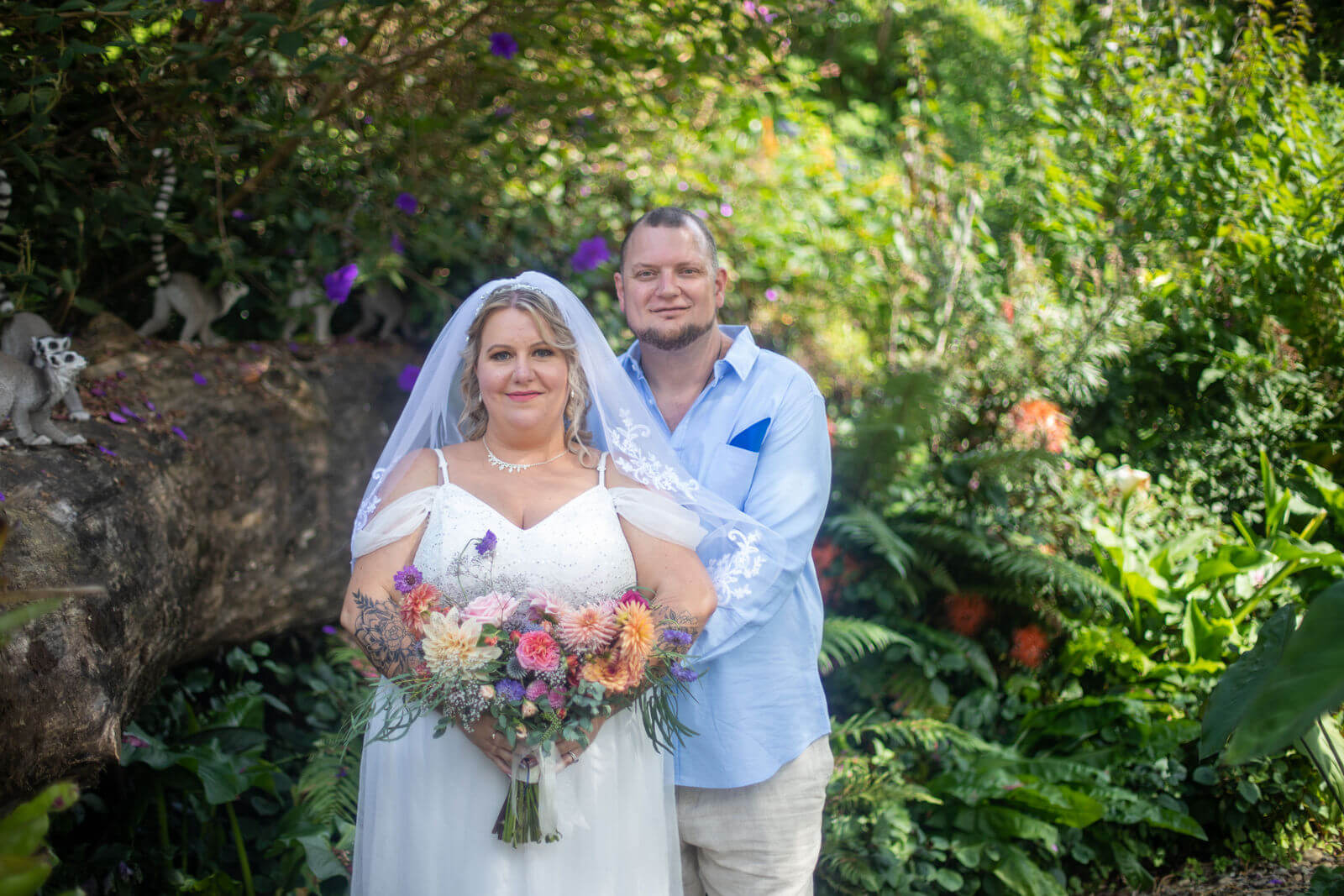 Auckland wedding photographer — couple smiling together in garden with wildflower bouquet