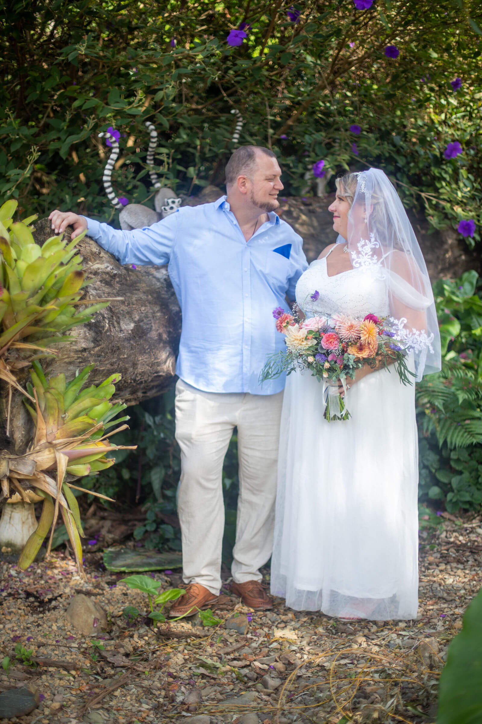 Auckland wedding photographer — couple in romantic garden setting with colourful bouquet