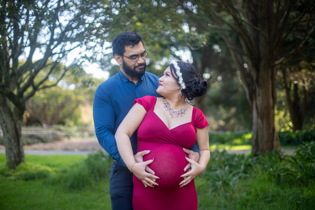 Auckland maternity photographer — couple in red gown in park